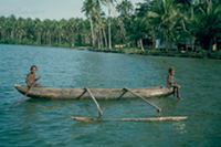 Boys in a homemade outrigger canoe, south coast of New Britain, Papua New Guinea